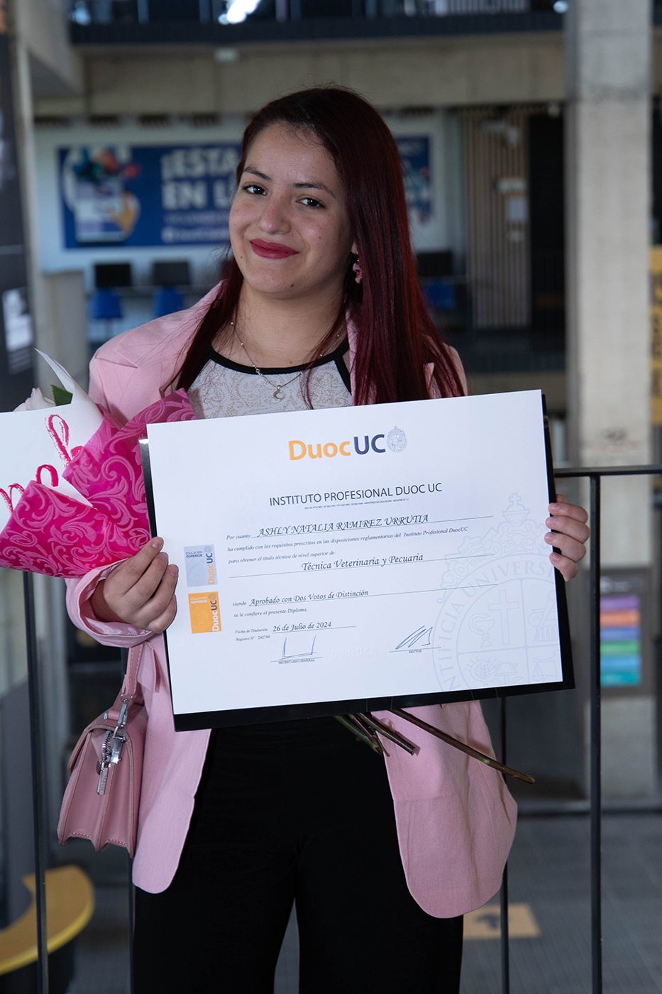 Titulada sonriendo con su diploma y flores